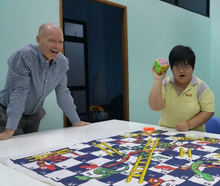 Microsoft volunteer, Henrik Salicath, Director Partner Sales, Dynamics Asia Pacific playing a game of Snakes and Ladders with SPD beneficiary, Sim Yee Yeh.