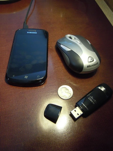 The Cisco Linksys AE1000 beside a Samsung Focus phone, US quarter and Microsoft Presenter Mouse