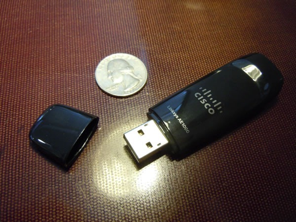 Cisco Linksys AE1000 dongle, with its cap off, placed beside a US quarter