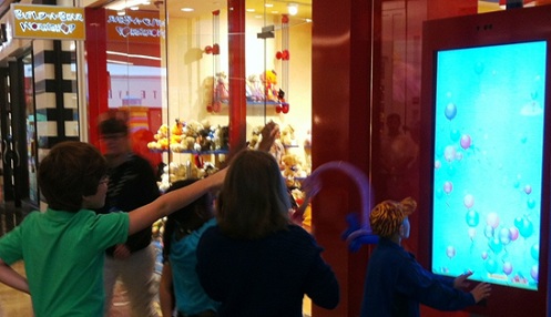 Children pop virtual balloons in a Kinect for Windows-enabled game at this Build-A-Bear store's front window.