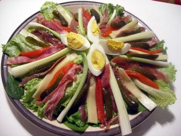 A salmagundi made of hard-boiled eggs, lettuce, cheese, red peppers, meat and pickles.