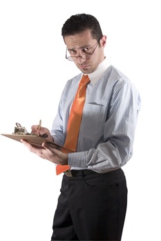 Businessman looking over his glasses with clipboard on hand - from side